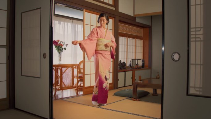 日本穿着传统服饰的女性。年轻美丽的日本女人穿着粉红色的和服和鲜花在家里摆姿势拍照。亚洲模特在镜头前展