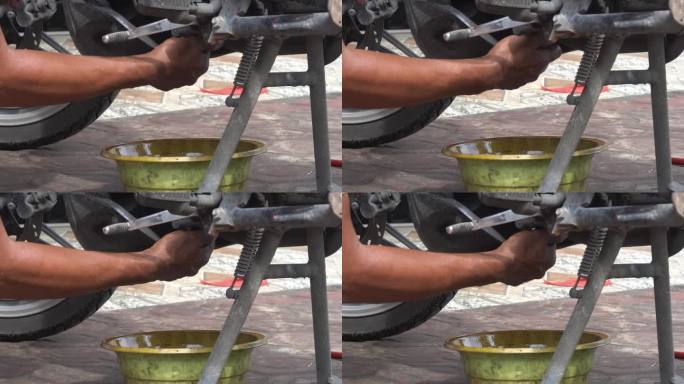 摩托车汽车机械师的手拧紧发动机缸体底部机油流出处的螺栓。换机油