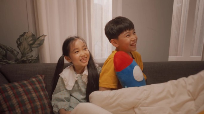 幸福的韩国家庭在家里共度美好时光:可爱的孩子们和父母一起玩躲猫猫，躲在毯子下面。孩子们开玩笑玩，享受