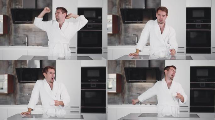 早上穿着浴袍的男人在厨房里打呵欠伸懒腰。实时