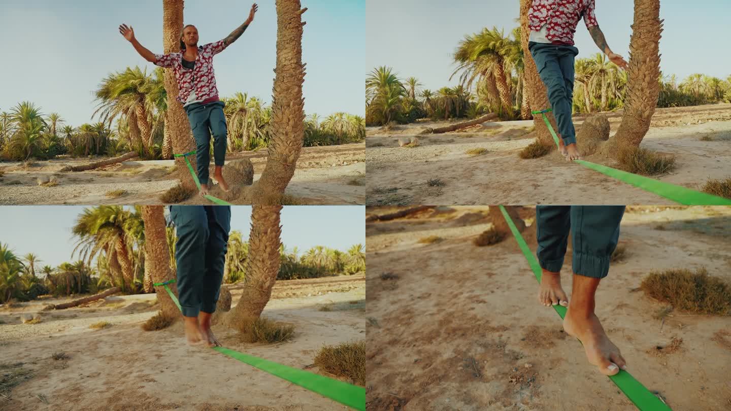 一名男性游客赤脚在沙滩上的棕榈树上走钢索保持平衡