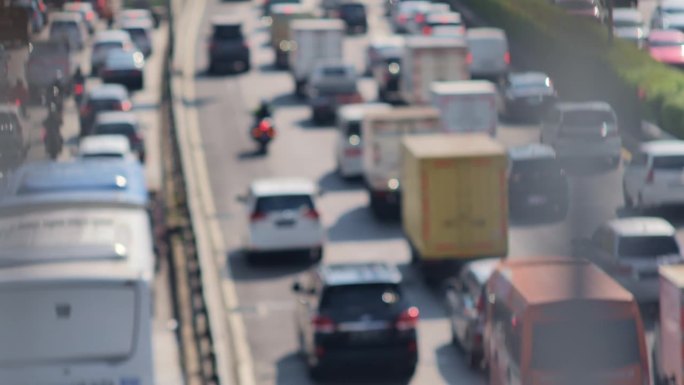 雅加达两条道路的城市交通密度模糊图像。一辆警用摩托车正在护送一位重要人物的车辆。描绘了高污染、高温、