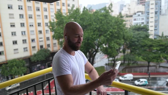 一名男子在建筑物的阳台上用手机拍照