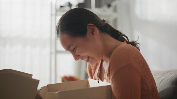 兴奋的亚洲女消费者打开纸板箱收到邮包