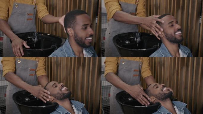 男理发师在理发店里准备给年轻的非裔美国人洗头
