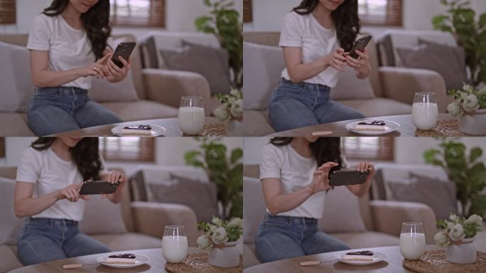 年轻漂亮的亚洲女性女士开心放松好玩用科技手机拍下美味的蛋糕甜点放在餐桌上的白色盘子上，现代社交网络习
