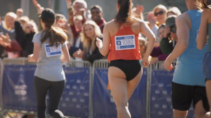 马拉松运动员在比赛中争夺第一名，向观众中的亲人挥手的慢镜头。支持者举着鼓舞人心的横幅欢呼