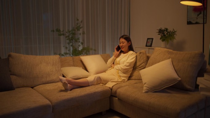 晚上，在她舒适的公寓里，一个美丽的韩国女人躺在沙发上放松，正在进行有趣的电话交谈，分享爱情和友谊的快