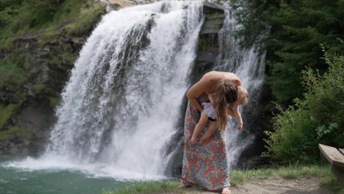 大自然中，母亲带着孩子站在瀑布前