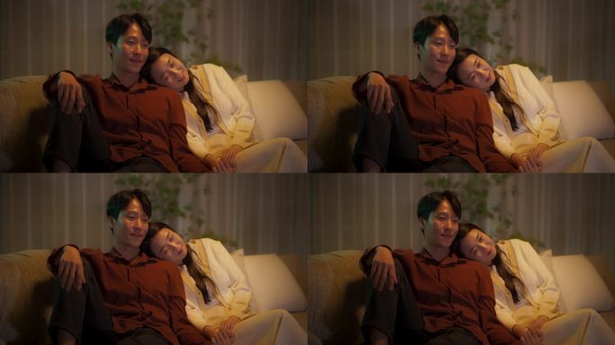 一对韩国夫妇在电视上观看浪漫喜剧电影的肖像。快乐的男朋友和女朋友一起在家享受有趣的电视连续剧，一起坐