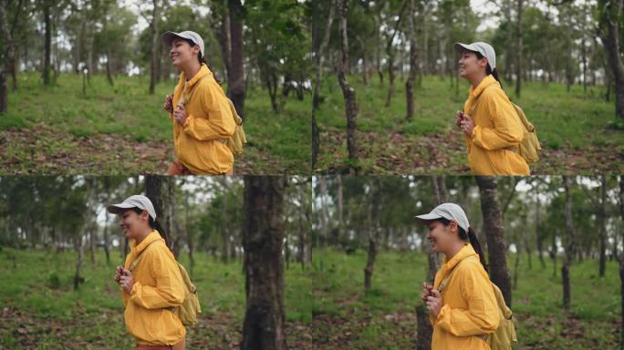 穿着黄色雨衣背着背包的女徒步旅行者在森林里徒步旅行