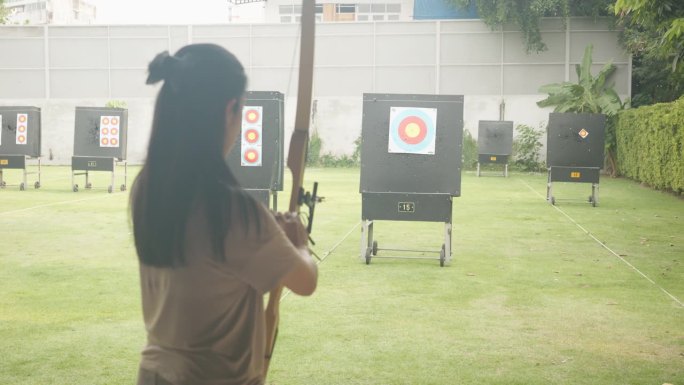 迷人的亚洲女性在靶场练习射箭。射箭。