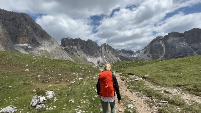 徒步穿越高山景观，欣赏绿色山丘和多石白云石山脉的美景