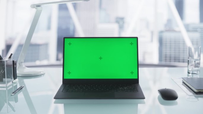 笔记本电脑模拟绿屏Chromakey显示器与运动跟踪站在办公桌上在一个现代公司总部。模板视频推广业务