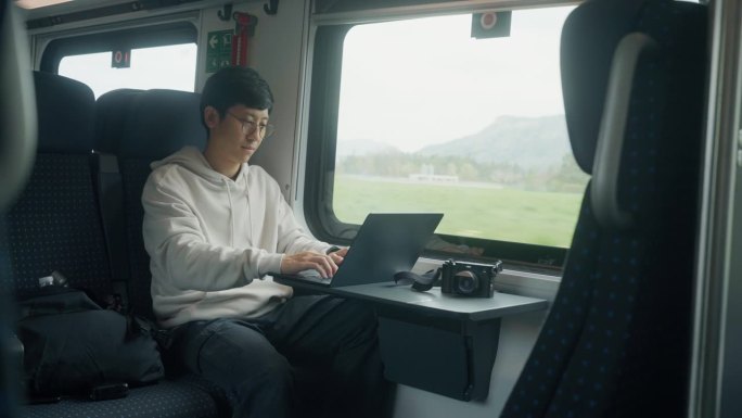 一个亚洲商人坐在火车上，一开始就望着窗外沉思。