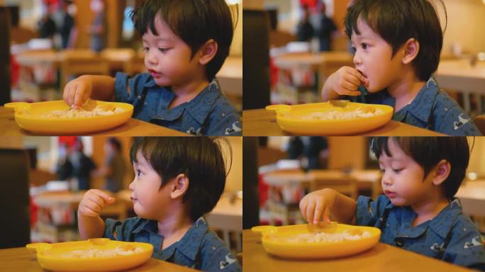 快乐的亚洲男孩用手吃日本面条。美味的。