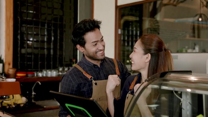 印度男子指着外卖机屏幕，显示女友在点餐今天咖啡店有很多订单。用爱轻轻地抚摸爱人的头。