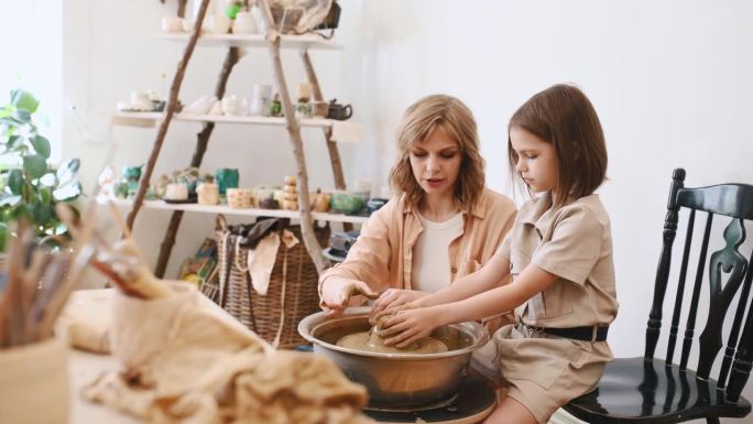 妇女正在教陶艺。妈妈带着小女孩。