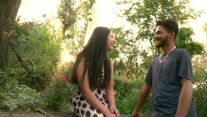 一对年轻的情侣在郁郁葱葱的公园里浪漫地共度时光。