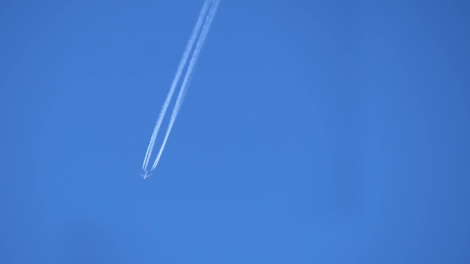一架商用客机在晴朗的蓝天中飞行的尾迹