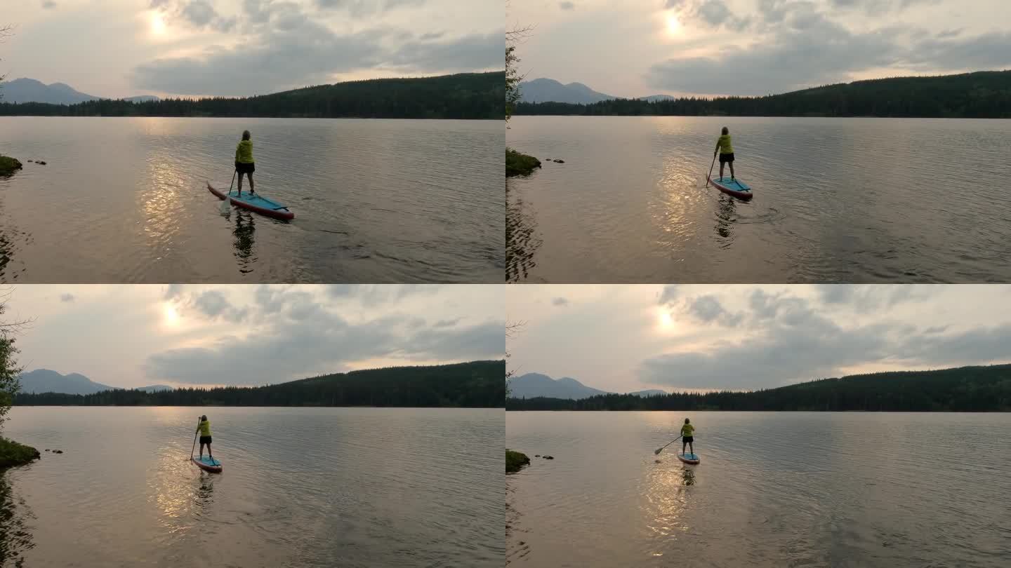 女子划桨板(SUP)穿过宁静的山间湖泊
