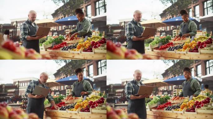 在农贸市场工作的国际成人伴侣。不同的夫妇在户外食品摊上出售生态水果和蔬菜。成年男性使用笔记本电脑与供