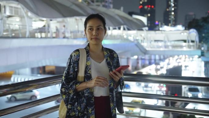 一名亚洲女子在拥挤的十字路口用手机导航时迷路了