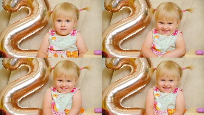 生日那天，一个两岁的小女孩头上扎着两个马尾辫，脸上挂着微笑