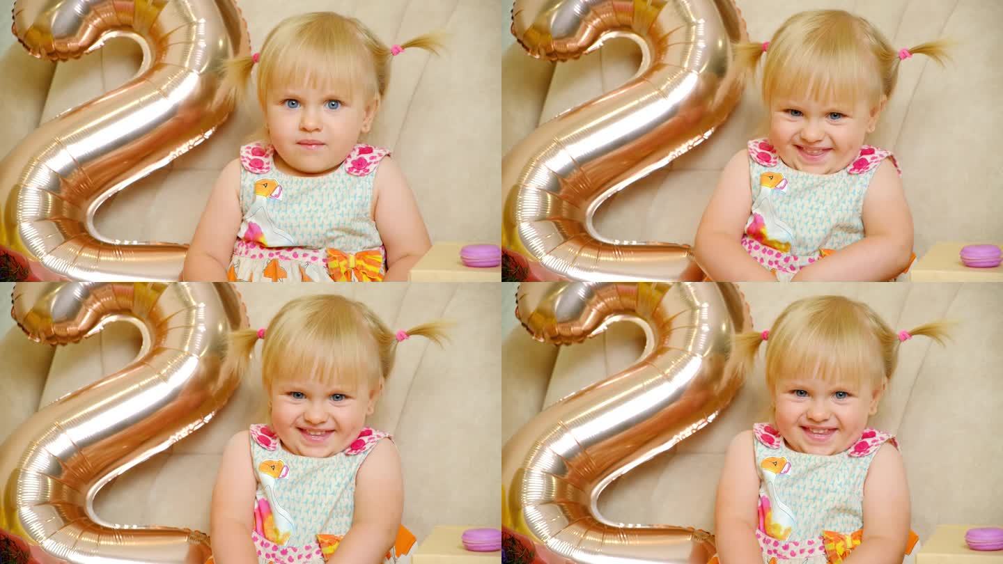 生日那天，一个两岁的小女孩头上扎着两个马尾辫，脸上挂着微笑
