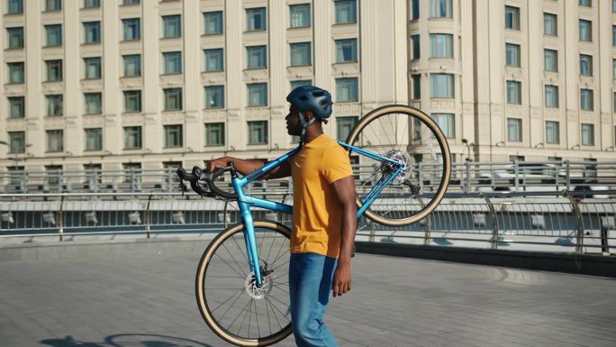 强壮的非裔美国人肩上扛着现代自行车