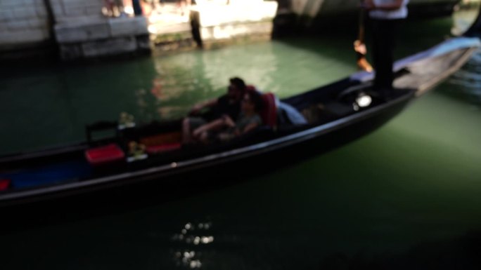 在意大利威尼斯的宫殿运河上，游客乘坐缆车漂浮在稻草桥下。