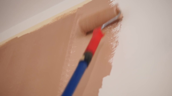 墙画。水性漆。辊绘画。修复。特写镜头。用油漆滚筒把白墙刷成粉红色。对公寓、房间、房子、公寓进行装修。