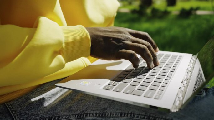 黑人在公园笔记本电脑键盘上打字的手，特写，工作和教育在线