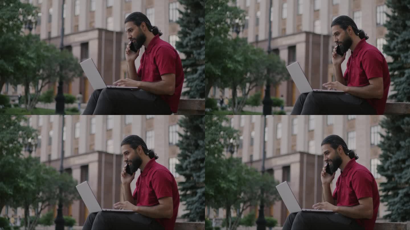 中东人坐在城市的户外，用笔记本电脑工作，用手机讨论想法