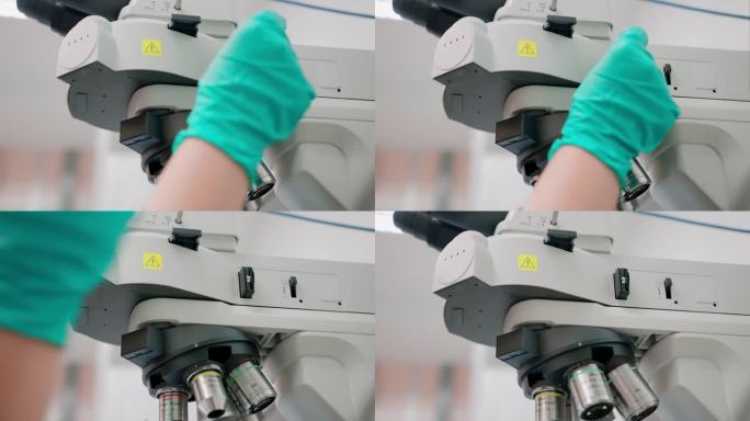 一位戴着防护手套的研究人员正在操作一台光学显微镜。与此同时，研究人员同时在仪器中放置一个偏光片，并调
