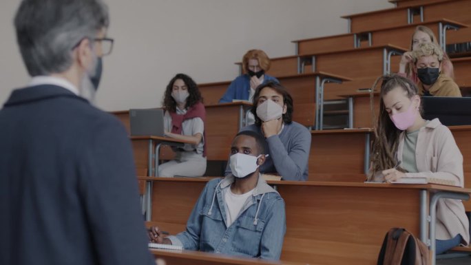 在covid-19全球大流行期间，戴着口罩的大学老师给学生讲课