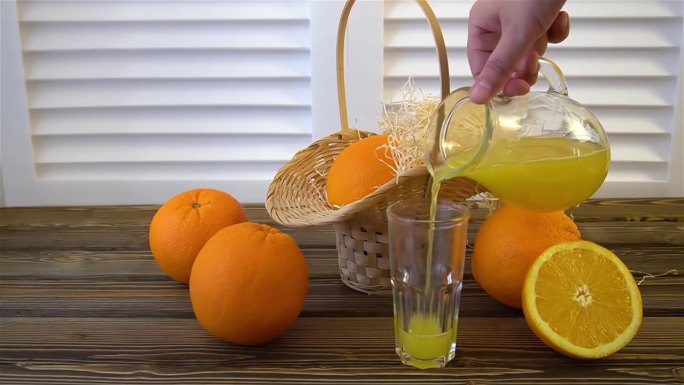 一个女人把桔子汁倒在摆着水果的漂亮桌子上