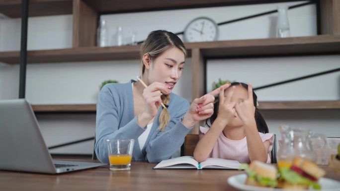 年轻的亚洲母亲教女儿做作业。母亲教女儿做数学作业。教育的概念