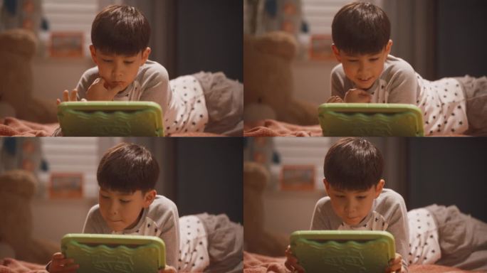 聪明的韩国男孩在孩子卧室的平板电脑上玩教育和学习游戏。快乐的孩子在赢得另一轮电子游戏后庆祝