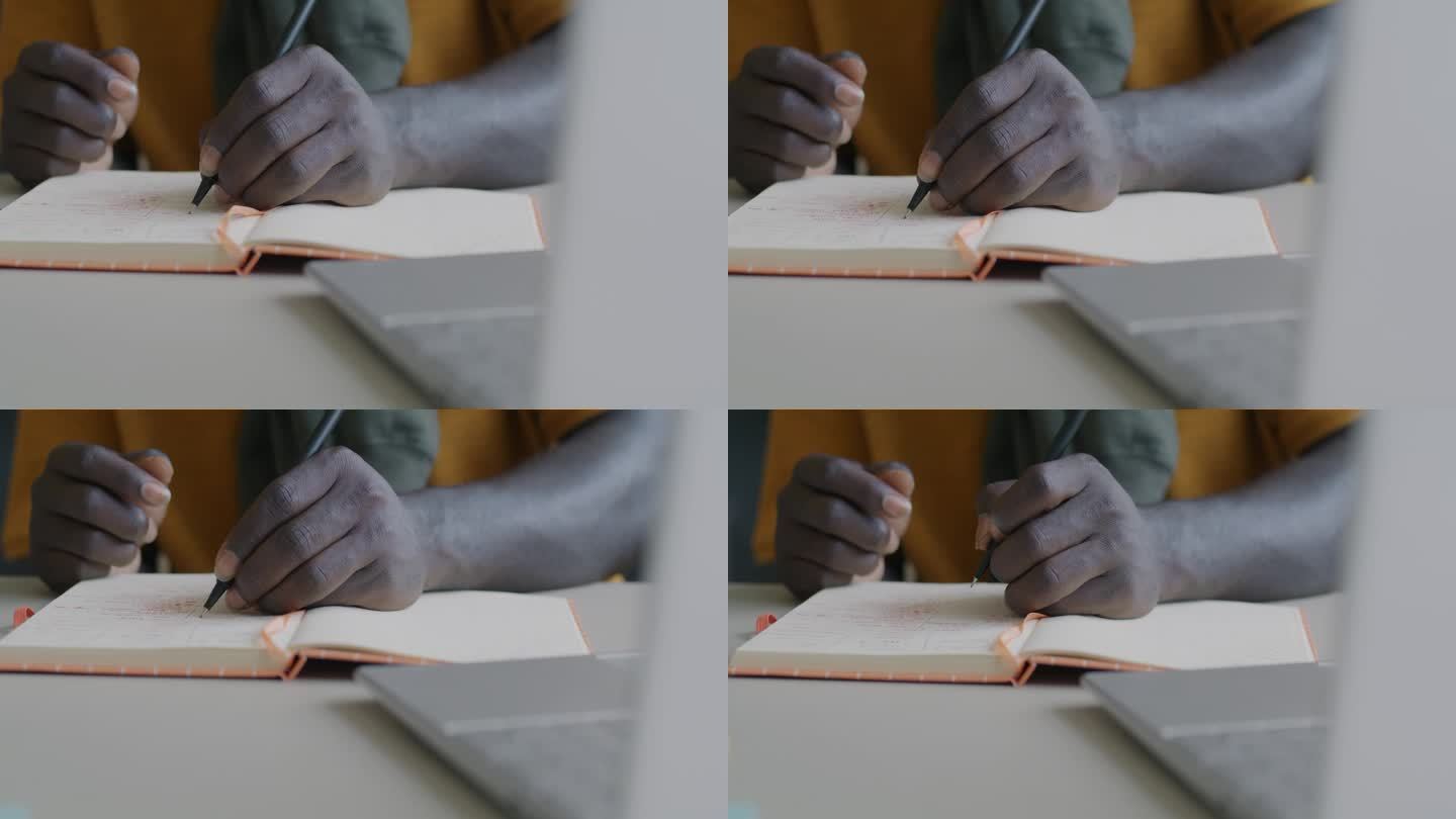 非裔美国人在家学习时，用手在笔记本上写信息的特写