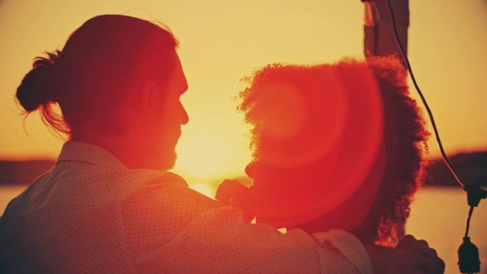 日落时分，一对夫妇手捧啤酒瓶，在船上欣赏海景