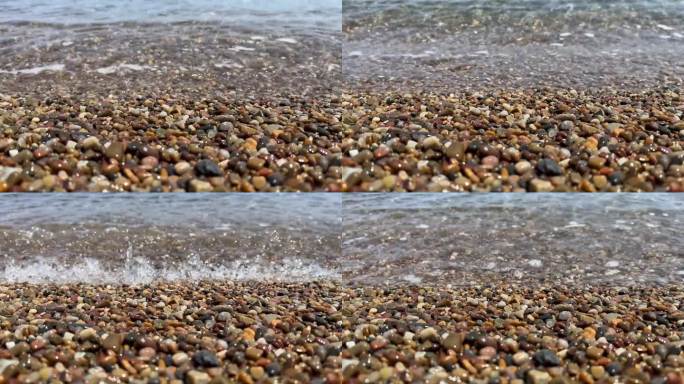 卵石滩的特写，透明的波浪和阳光照射在水面上。石质海岸的近景。自然背景的平静的大海在冲浪区