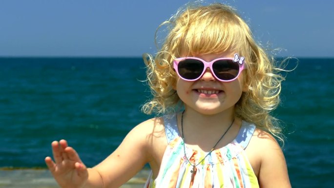 沙滩上戴墨镜的有趣小女孩