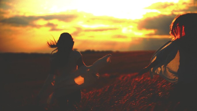 慢镜头:夕阳下，橙色的天空下，闺蜜在麦田里奔跑