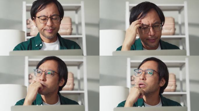 压力日本亚裔男性在家里用笔记本电脑工作，不开心，消极的工作项目麻烦，悲伤，焦虑，担心严重的在家工作
