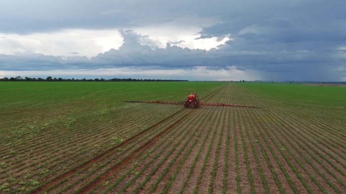 利用计算机技术在大豆种植园上施用农药的拖拉机鸟瞰图。主题视频收藏。