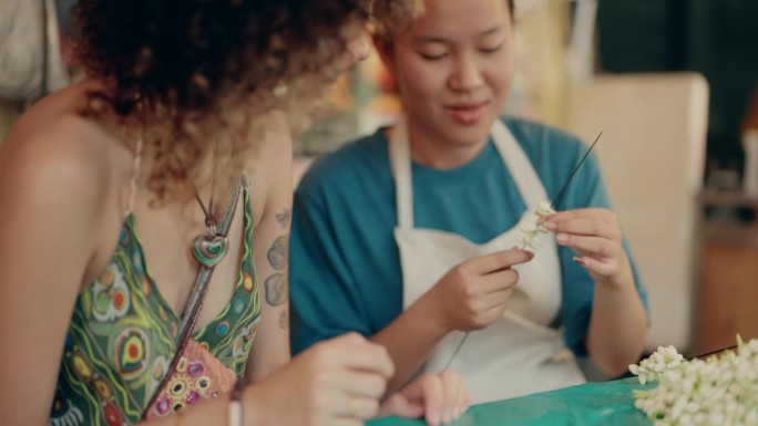 亚洲游客周末在曼谷的泰国花店学习花环制作。