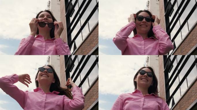 一位迷人、自信的女商人站在一座现代建筑的背景下，看着她的正前方，戴上太阳镜，拉直头发。慢动作