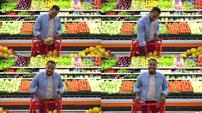 一位快乐的黑人顾客在超市把一个南瓜放进购物车，然后面对镜头微笑