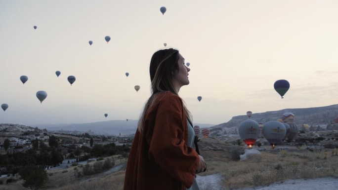 快乐的年轻美丽的游客，女摄影师用胶片相机拍摄热气球天空风景。